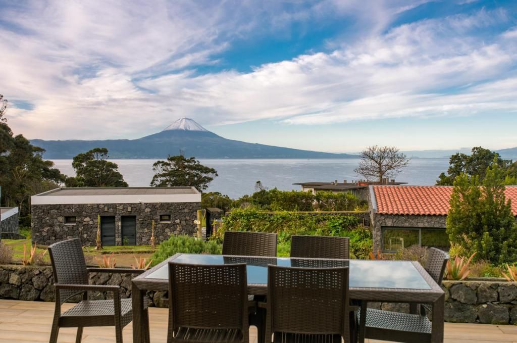 A patio with a table and chairs overlooking a body of water and a mountain.