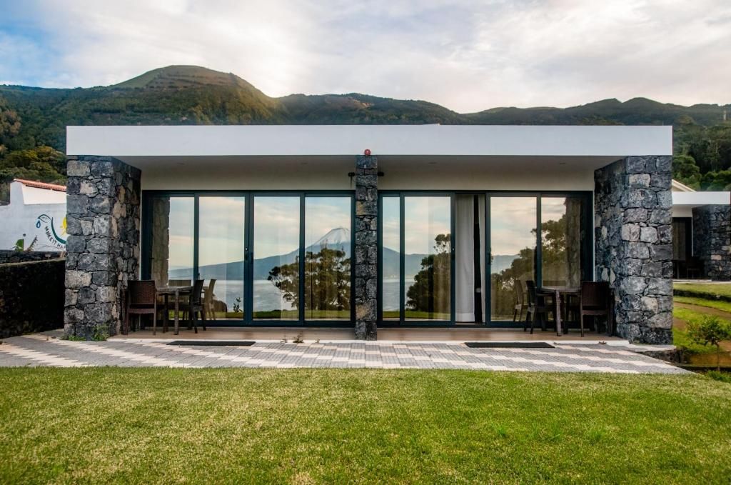 Een modern gebouw met een stenen gevel, grote glasramen en uitzicht op een berg.