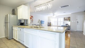 Una cucina moderna con mobili bianchi, un piano di lavoro in granito e un frigorifero in acciaio inossidabile.