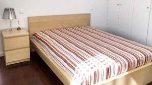 Ein Schlafzimmer mit einem hölzernen Bett, einem Nachttisch mit Lampe und einem weißen Kleiderschrank.