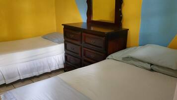 A bedroom with two single beds, a dresser, and a mirror.