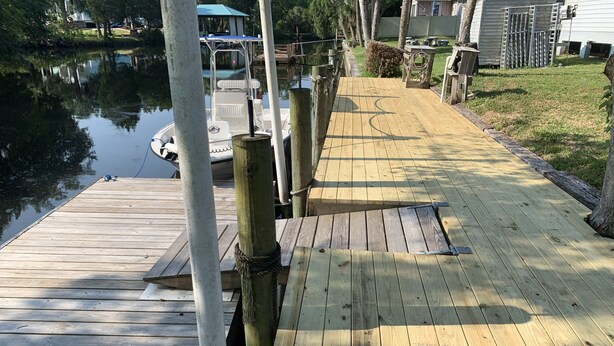Un muelle de madera que se adentra en aguas tranquilas, con un bote amarrado al final.