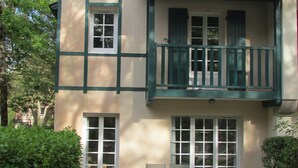 Ein zweistöckiges Gebäude mit Balkon, zahlreichen Fenstern und einem Ziegeldach.
