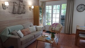 Ein gemütliches Wohnzimmer mit Sofa, Sessel, Couchtisch und einem fenster mit Vorhängen.
