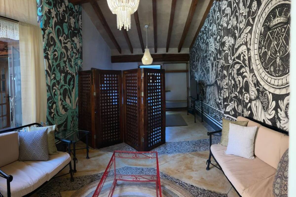 A room with a sofa, a glass table, a patterned wall, and a wooden partition.