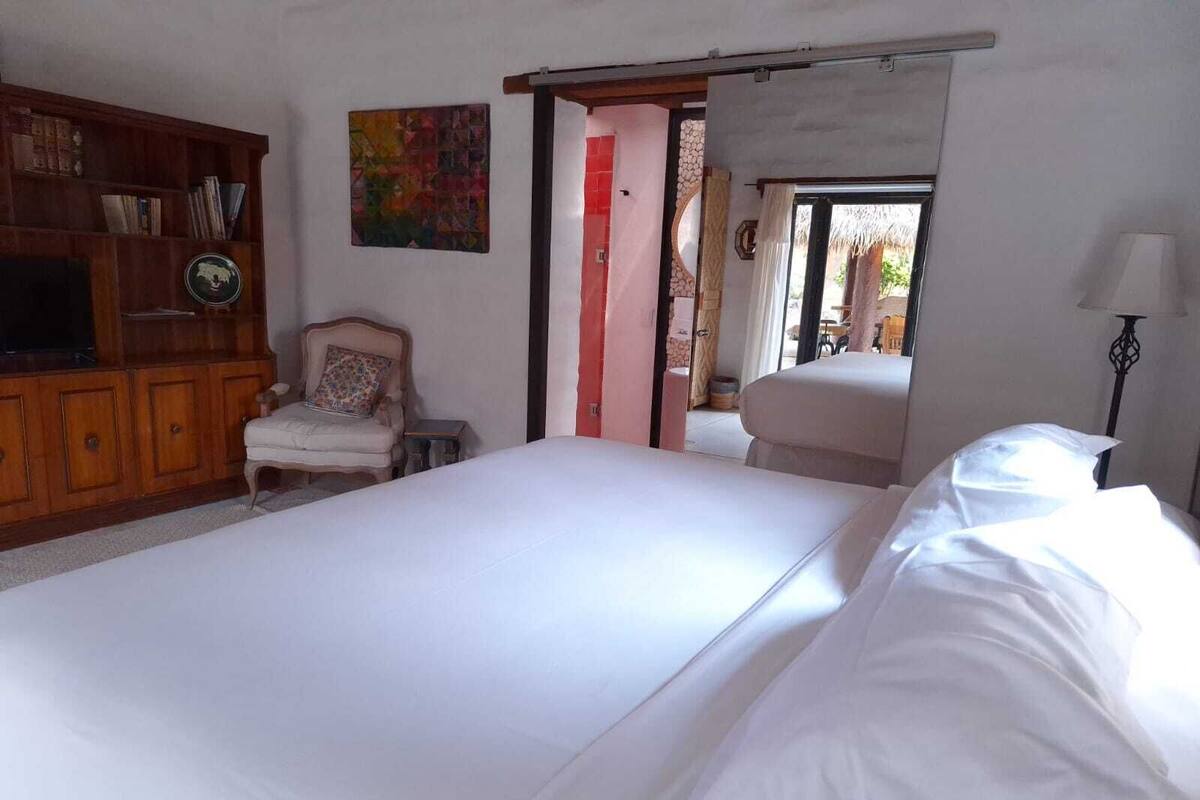 A bedroom with a large bed, a wooden dresser, a chair, and a painting on the wall.