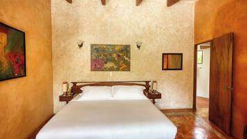 A hotel room with a large bed, wooden headboard, two bedside tables, and a painting on the wall.