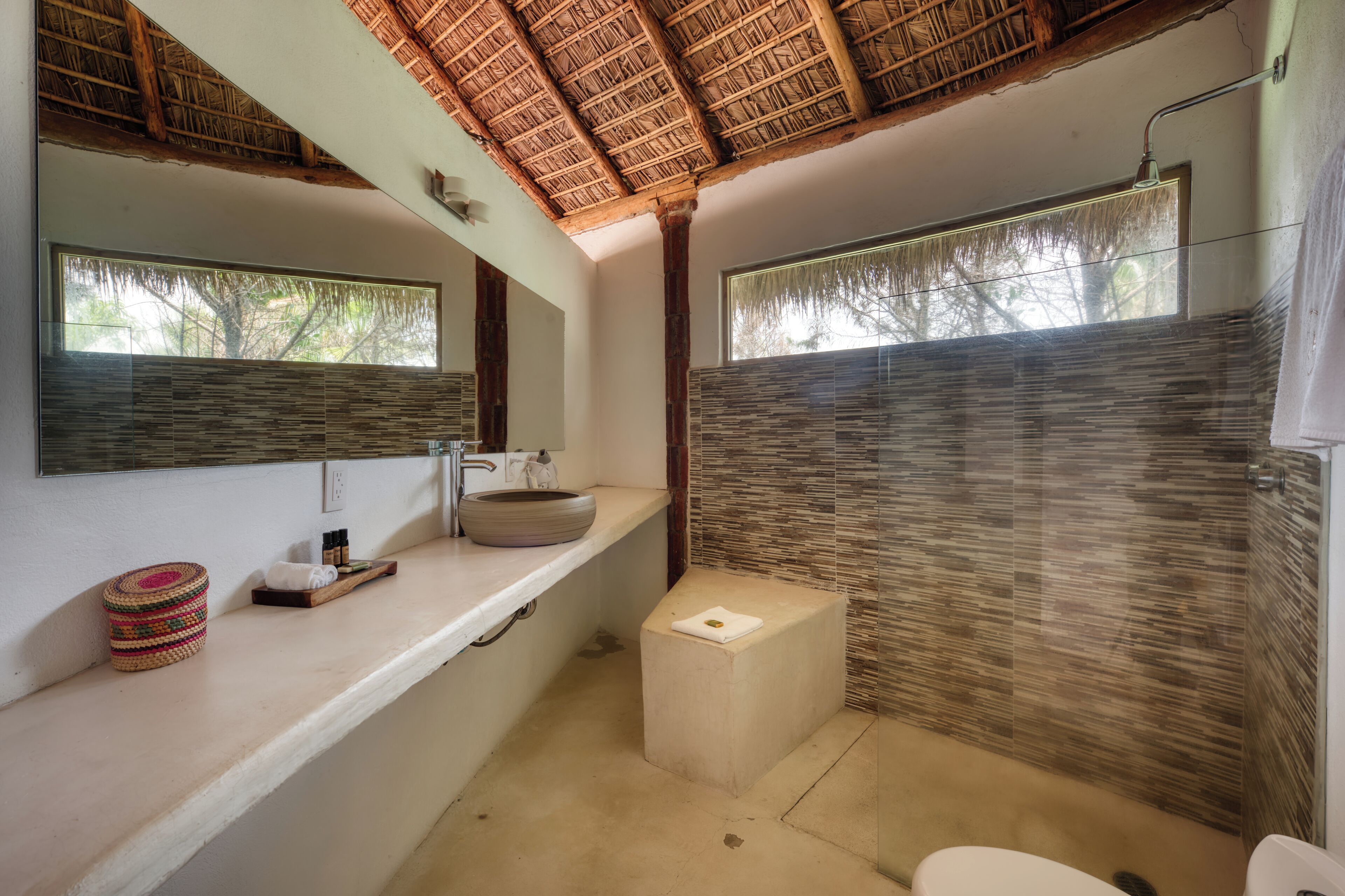 A bathroom with a modern design, featuring a large mirror, a round sink, and a shower area.