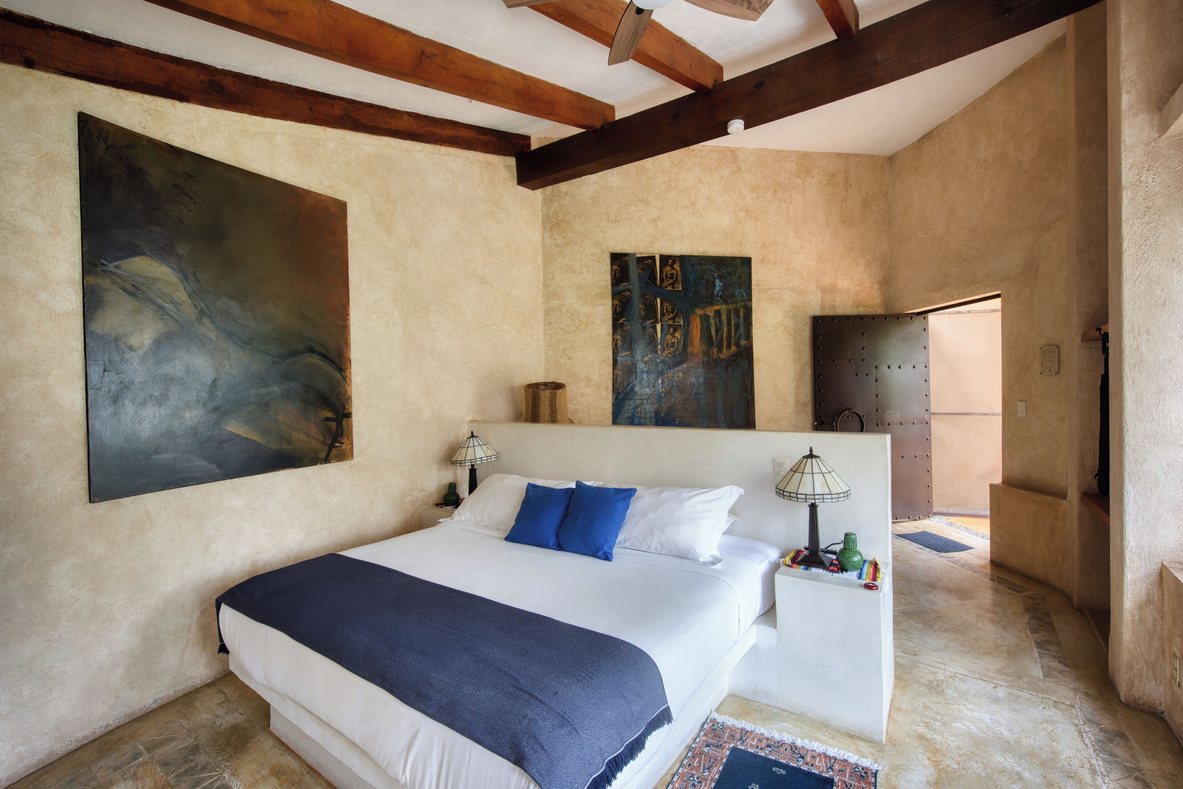 A bedroom with a large bed, two bedside tables, and artwork on the walls.