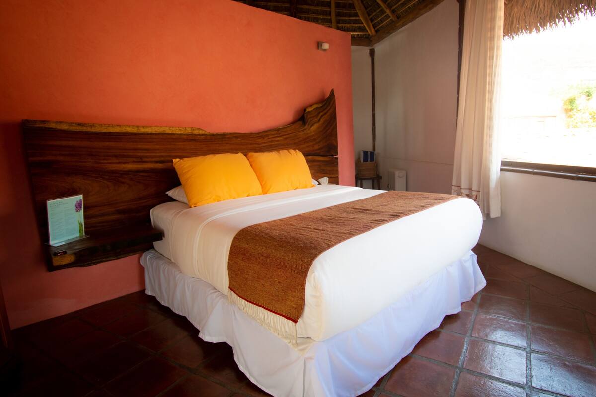 A bed with a wooden headboard, white bedding, and a brown throw blanket.
