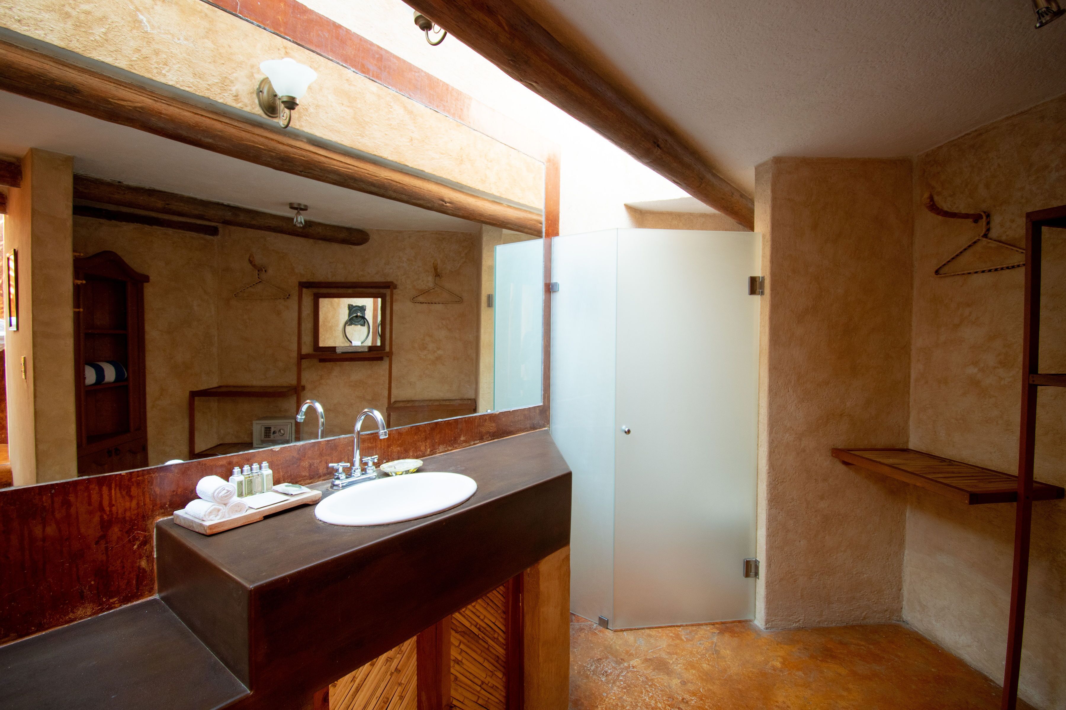 A bathroom with a wooden vanity, a large mirror, a white sink, and a towel rack.