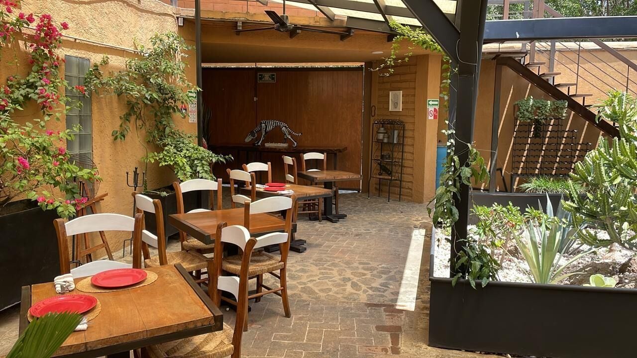 An outdoor patio with wooden tables and chairs, a staircase, and potted plants.