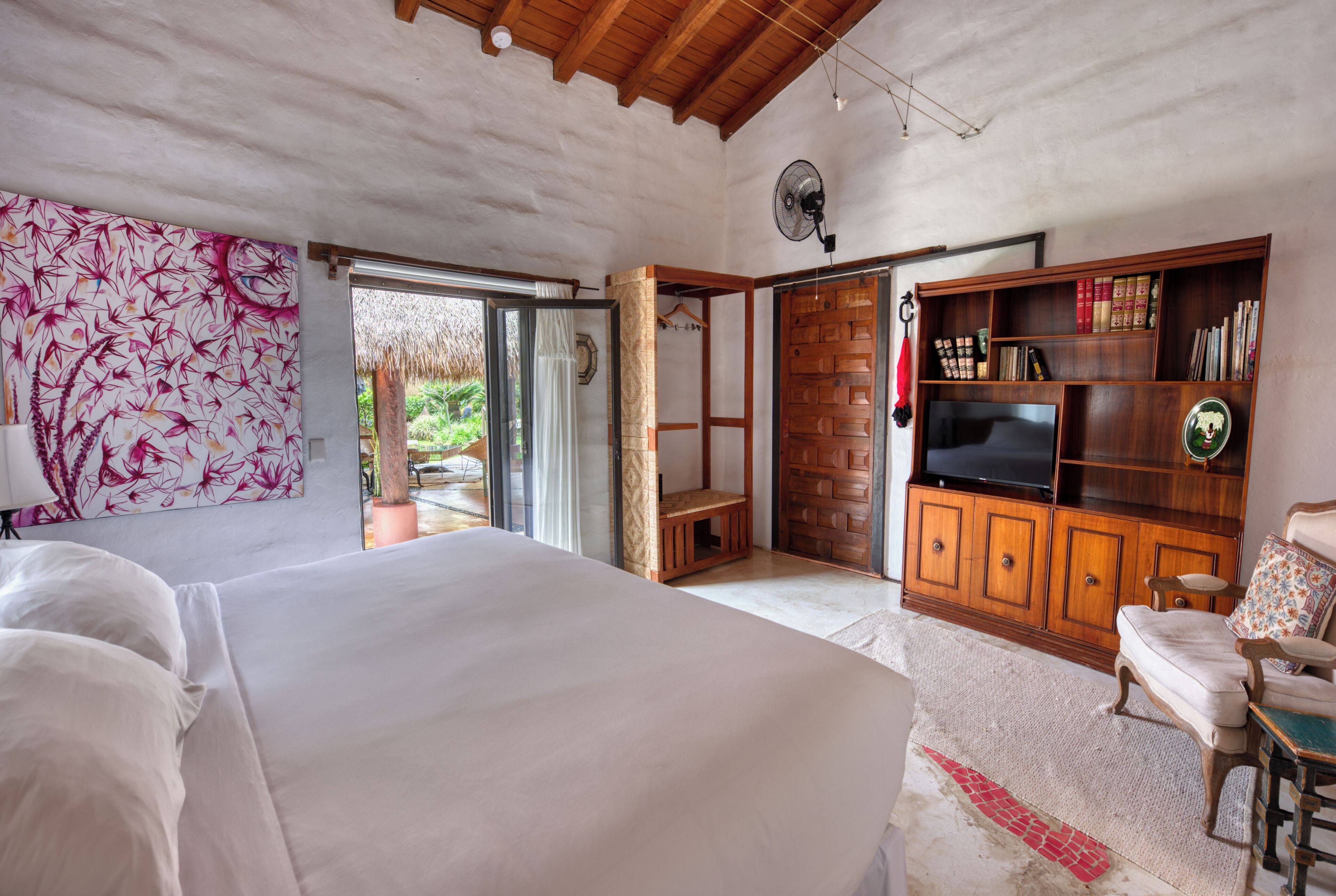 A bedroom with a large bed, a wooden cabinet with a television, and a bookshelf.