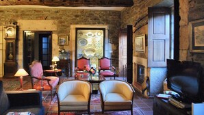 Un salon chaleureux avec des murs en pierre, une cheminée, un téléviseur et des fauteuils confortables.