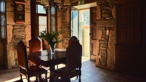 Un coin repas avec un mur en pierre, des meubles en bois et une horloge.