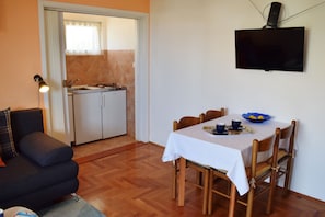 Cozy living space with a dining area and kitchenette, featuring a flat-screen TV, dining table, and comfortable seating.