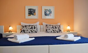 A hotel room with a bed, two bedside lamps, two pillows with paisley patterns, and two wall-mounted abstract paintings. - Peaceful location, walk everywhere + parking free (Hvar)