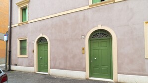 Un edificio con dos puertas verdes, cada una con un pequeño ventanal encima.