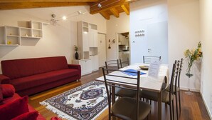 Una sala acogedora con un sofá rojo, una mesa de comedor con sillas y un tapete estampado.