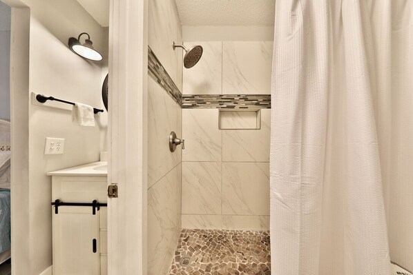 A bathroom with a shower, a towel rack, and a mirror.