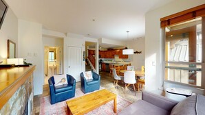 Un salon spacieux comprenant un canapé, deux fauteuils, une table basse et un coin repas avec une table et des chaises.