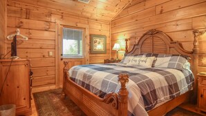 A wooden cabin bedroom with a bed, nightstands, a dresser, and a window with blinds. - Smoky Mountain Top Cabin, New Hot Tub, 10 mins to Gatlinburg or Pigeon Forge (Sevierville)