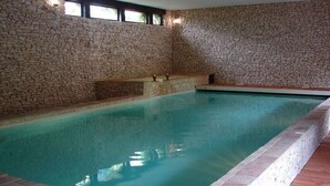 Ein Hallenbad mit Steinwänden und einer gefliesten Kante.