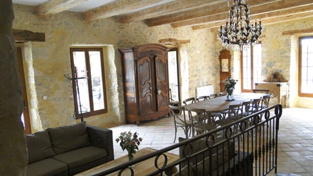 Ein rustikales Interieur mit freiliegenden Steinwänden, einem Holztisch mit Stühlen, einer Couch und einer Kristallleuchter.