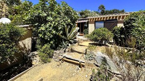 Ein Haus mit Natursteinfassade, einer Holzterrasse und verschiedenen Wüstenpflanzen.