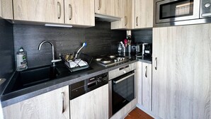 Eine moderne Küche mit hellen Holzschränken, Edelstahlgeräten und einer schwarzen Arbeitsplatte.
