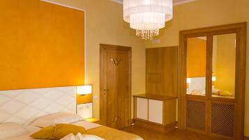 Una habitación de hotel con cama, lámparas de noche, armario y espejo.