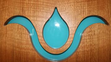 A teal-colored, teardrop-shaped object with a black outline on a wooden surface.