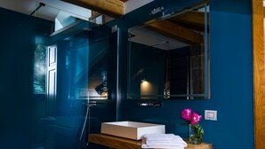 Un baño moderno con cabina de ducha de vidrio, tocador de madera y un espejo grande.
