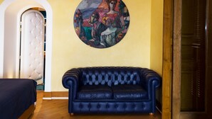 Una habitación con un sofá de cuero azul, un cabecero acolchado y un cuadro en la pared.