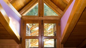 Ventana de desván con marco de madera y vista a árboles.