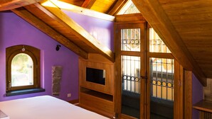 Un dormitorio con techo de madera, televisor empotrado, ventana y puerta con vidrio de seguridad.