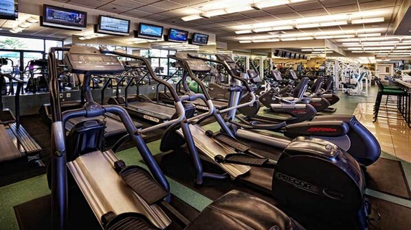 Une salle de sport équipée de plusieurs tapis de course, de vélos d’appartement et d’appareils de musculation.