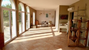 Una habitación amplia con ventanas grandes, un comedor y una sala de estar.