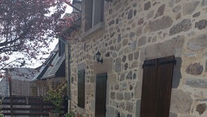 Ein Steinhaus mit Innenhof, Blumentöpfen und einem Holztor.