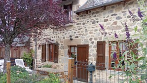 Ein Steinhaus mit Holzhörnern, einem Metallgitter und einem Garten mit verschiedenen Pflanzen.