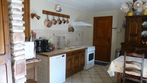 Een keuken met een vaatwasser, fornuis en diverse keukengerei aan de muur.