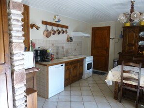 A kitchen with a dishwasher, stove, and various kitchen utensils on the wall. - giteduplombducantal to the guards in Saint-Jacques-Des-Blats (Saint-Jacques-des-Blats)