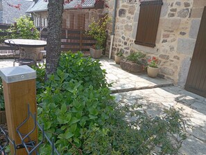 Edificio de piedra con puerta de madera, reja metálica y plantas en macetas.