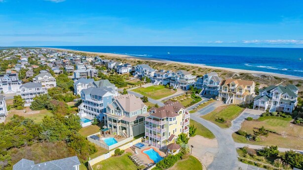 A coastal residential area with houses, a swimming pool, and a beach in the background. - Semi-Oceanfront Premier Home w/ Pool, Hot Tub, Elevator, Game Room, and Theater (Avon)