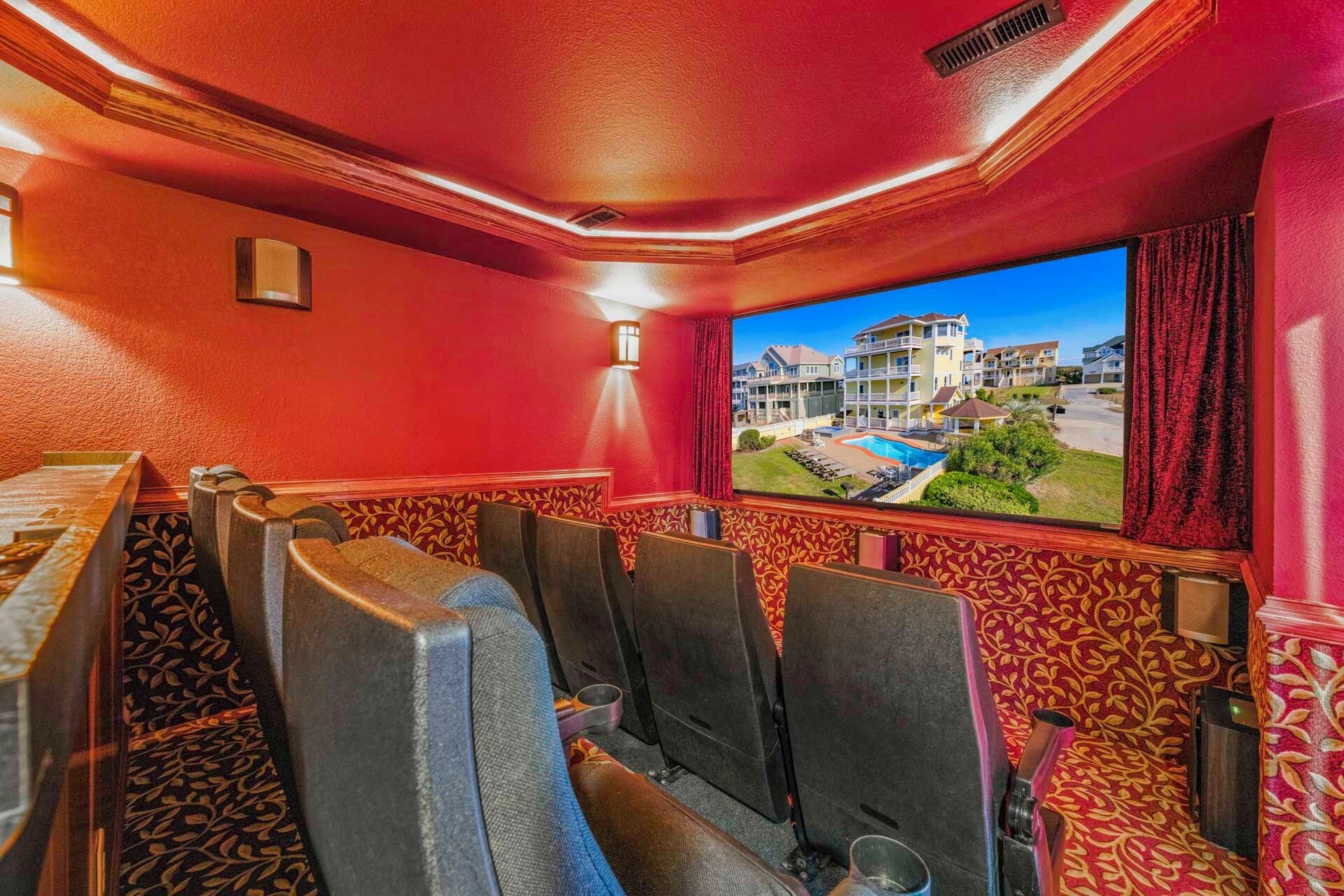 Una habitación con paredes rojas, alfombra estampada y un ventanal con vistas a una piscina y edificios.