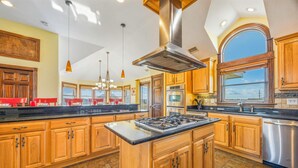 A spacious kitchen with wooden cabinets, a central island, stainless steel appliances, and pendant lighting. - Semi-Oceanfront Premier Home w/ Pool, Hot Tub, Elevator, Game Room, and Theater (Avon)