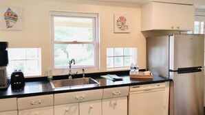 A kitchen with a stainless steel sink, a refrigerator, and white cabinets. There are two windows providing natural light. - Unit2 GR8 LOCATION mins to Longwood Medical Area, BC, BU, HarvMedSchool SPACIOUS (Brookline)