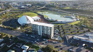 Vista aérea de un edificio moderno con una gran estructura circular, rodeado de carreteras y vegetación.