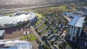 Vista aérea de una zona comercial con un amplio estacionamiento, un estadio y edificios modernos.