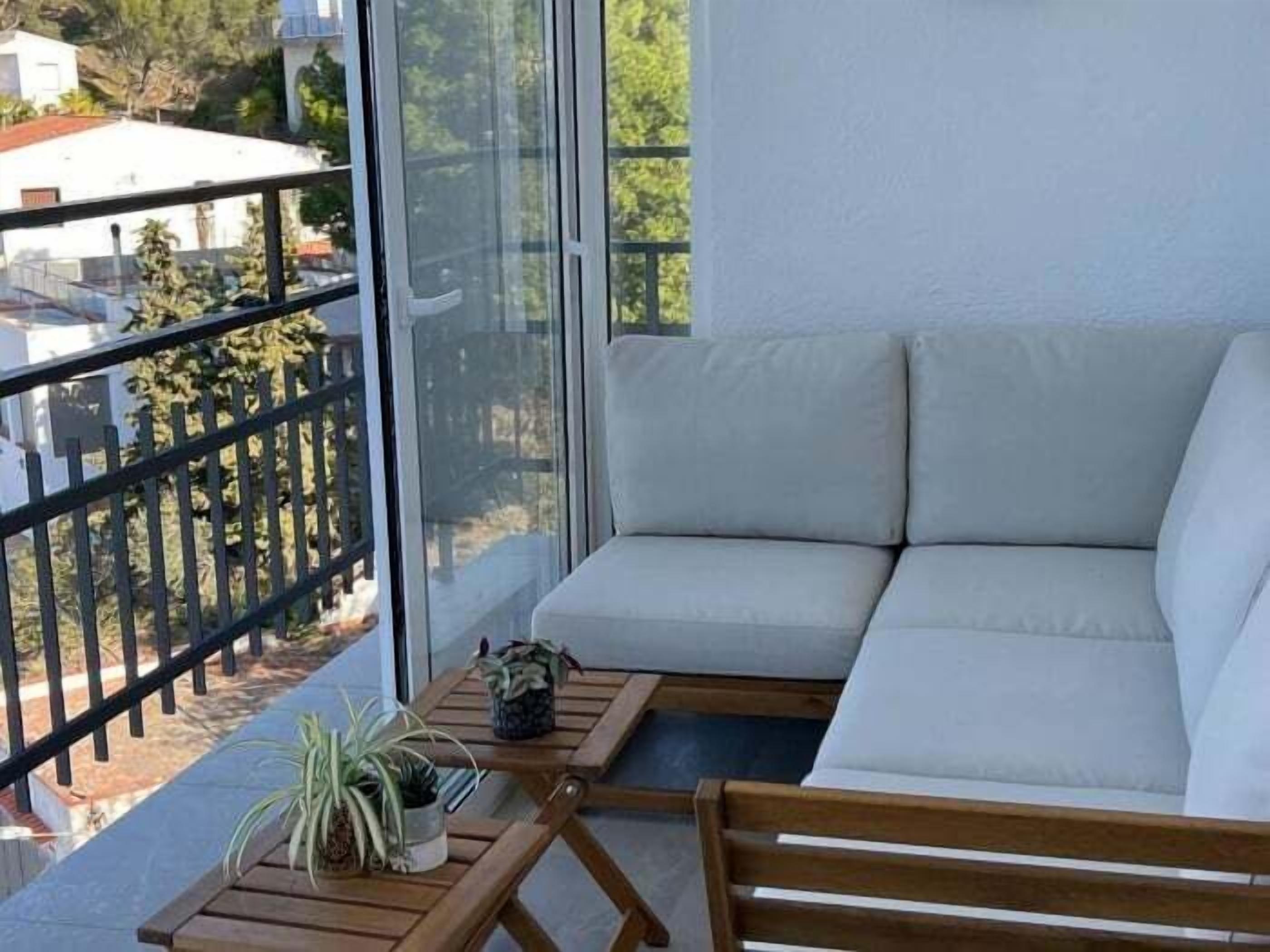 A balcony with a sofa, a small table, and potted plants.